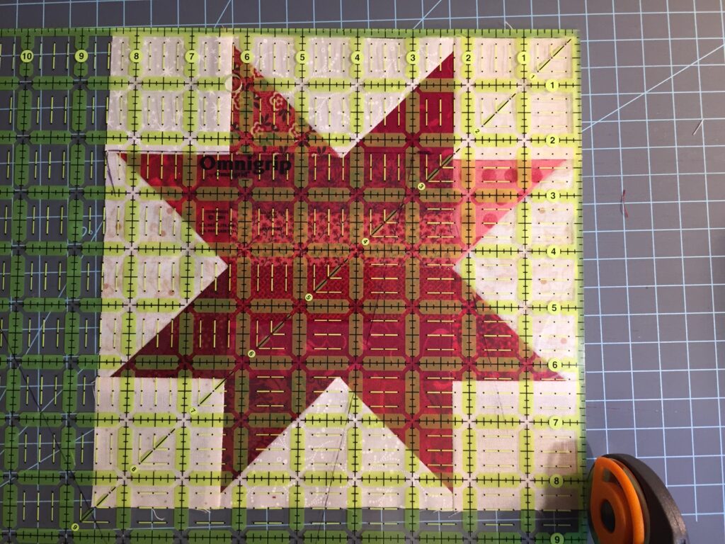 trimming quilt block with rotary cutter and plastic ruler