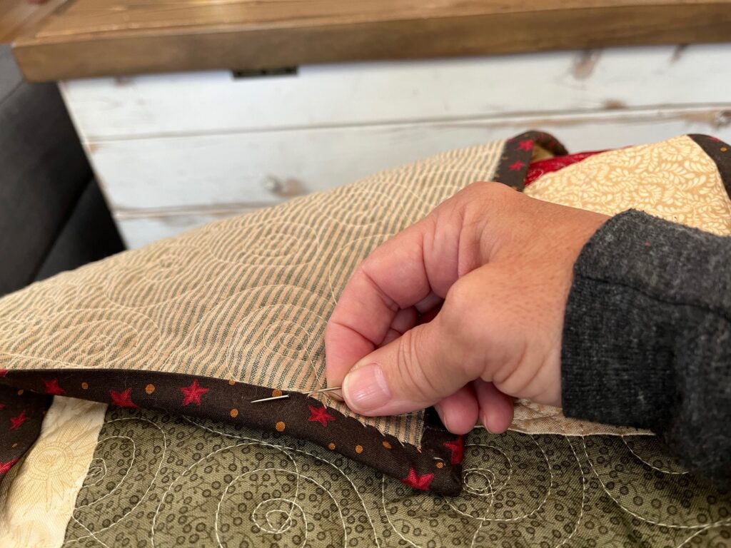 hand stitching the binding to the quilt back